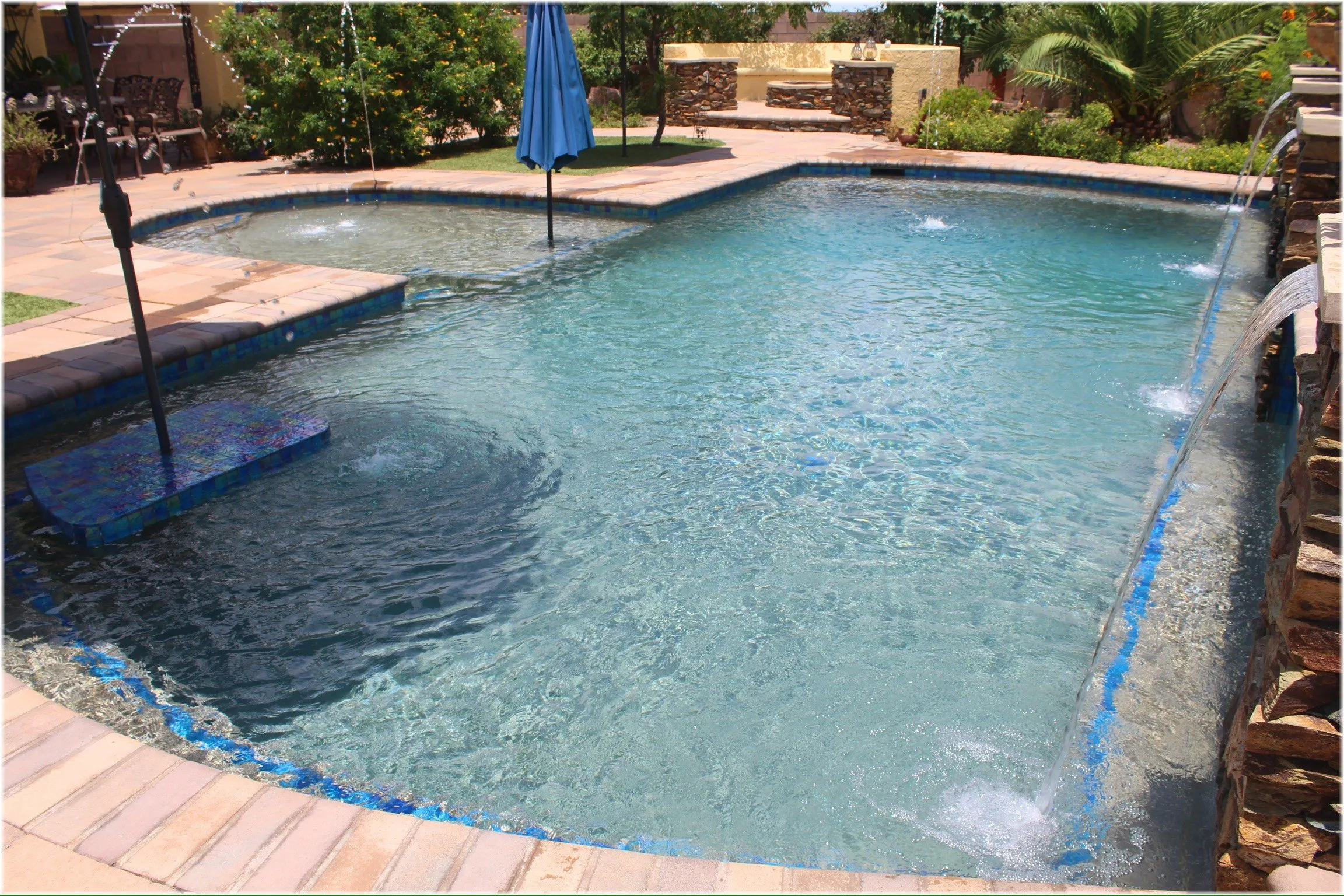 Freeform pool with glass tile waterline in a desert backyard