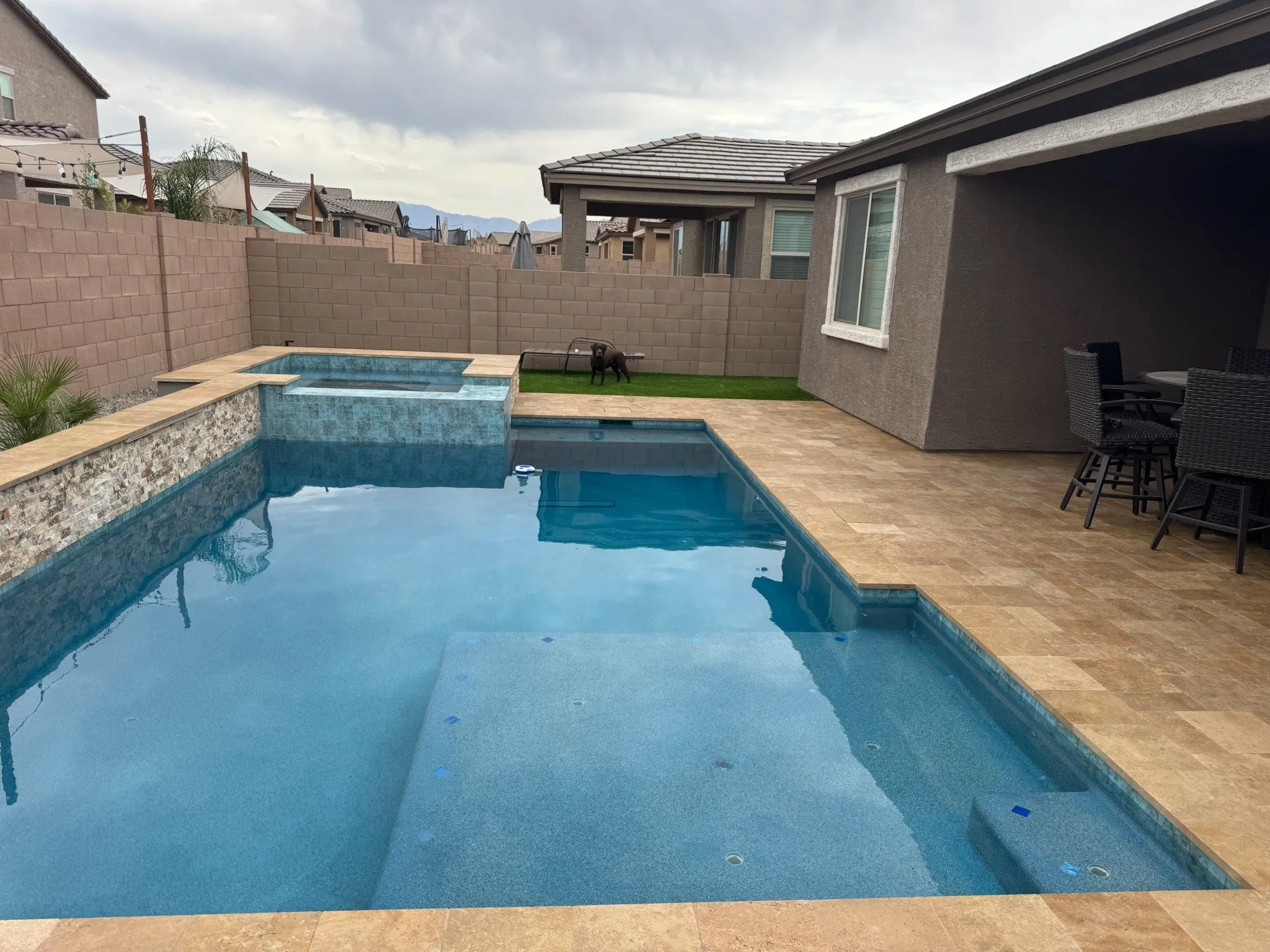 Geometric pool and raised spa with travertine decking